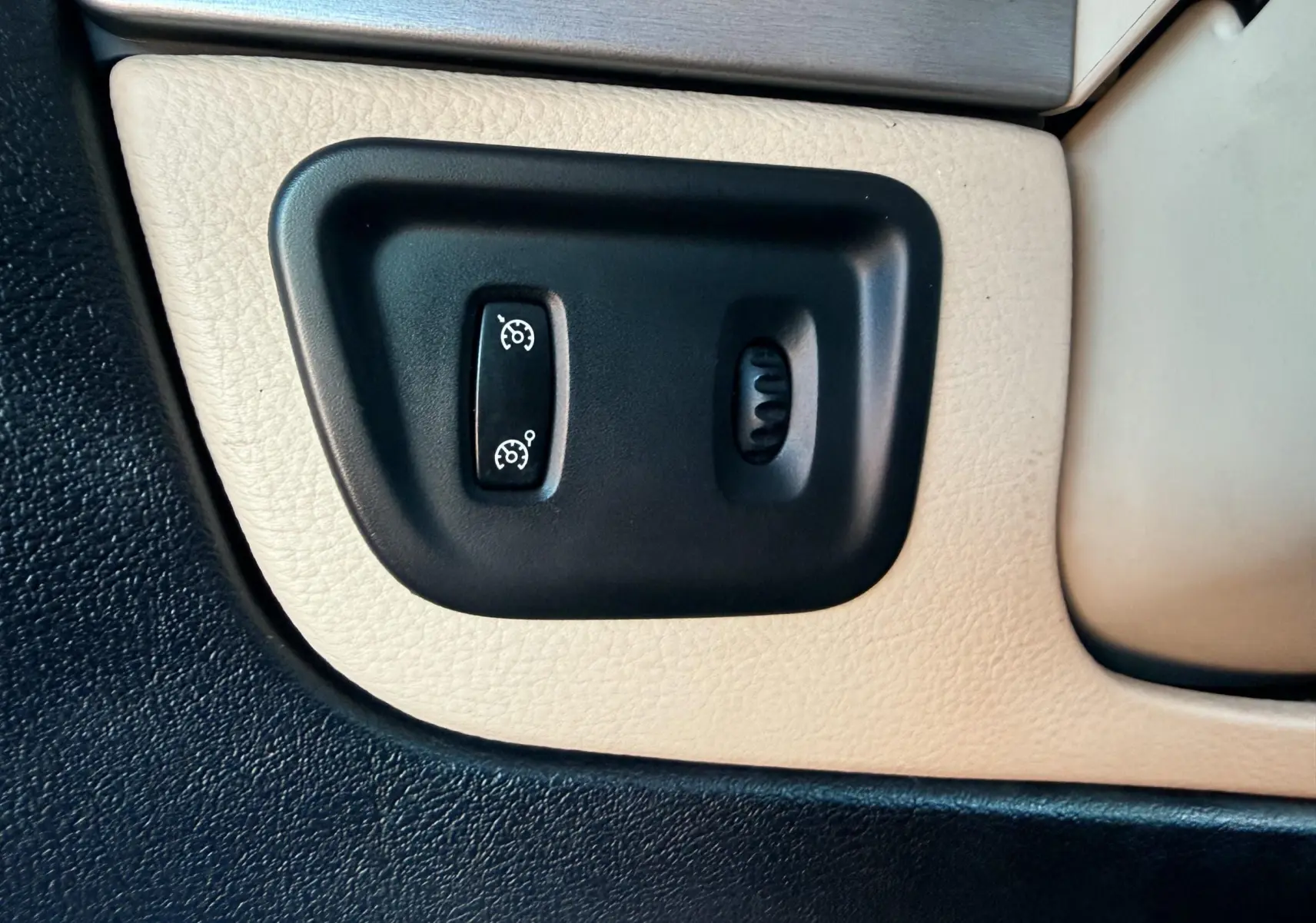 Gros plan sur les commandes de régulateur de vitesse intégrées dans la garniture beige de la porte côté conducteur du Renault Avantime gris.