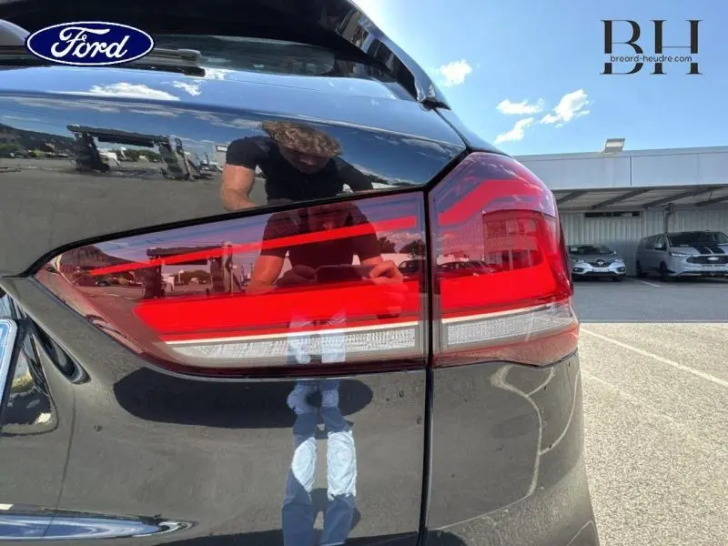 Gros plan sur le feu arrière droit d'une BMW X1 xDrive25eA 2021 en Saphirschwarz, reflétant l'environnement extérieur.