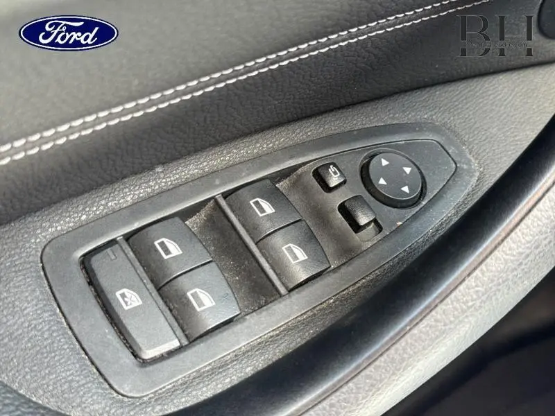 Panneau de commandes des vitres et rétroviseurs sur la portière intérieure d'une BMW X1 Saphirschwarz, vue rapprochée.