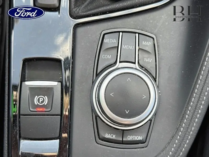 Gros plan sur la molette de commande multimédia et le frein à main électrique dans l'habitacle d'un BMW X1 noir Saphirschwarz