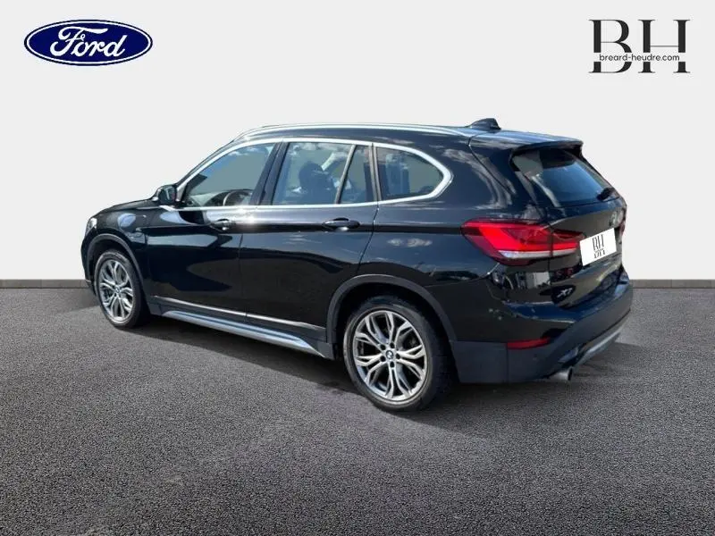 BMW X1 xDrive25eA 220ch xLine noir saphir, vue 3/4 arrière côté gauche avec jantes alu et feux LED arrière.