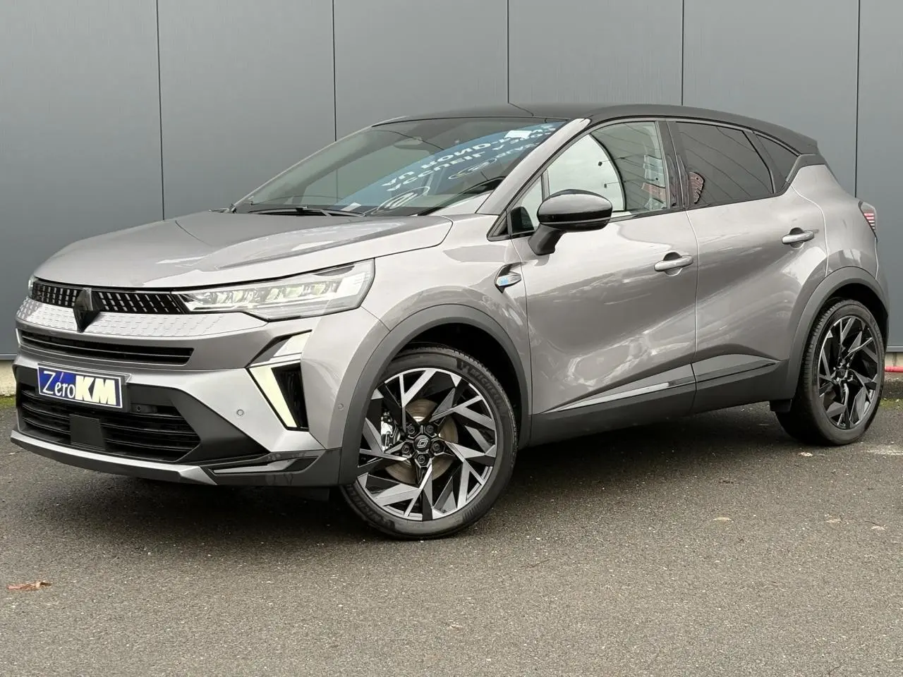 Renault Captur 2025 gris Cassiopée avec toit noir, vue 3/4 avant côté gauche, jantes aluminium 19 pouces Elixir.