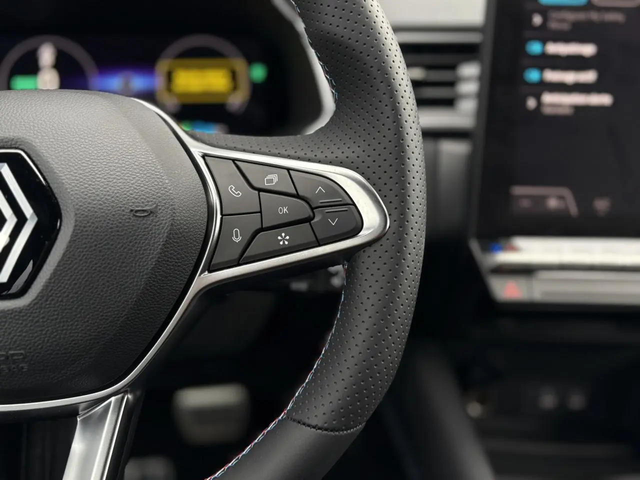 Gros plan sur le volant perforé noir avec surpiqûres bleu blanc rouge du Renault Captur Esprit Alpine 2025.