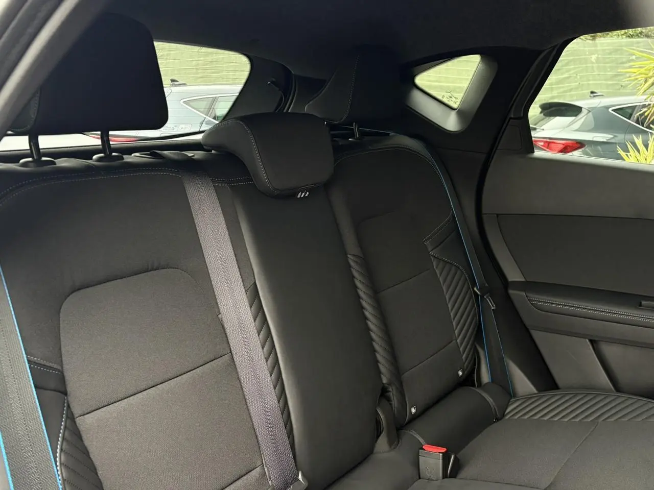 Vue intérieure côté droit des sièges arrière noirs avec surpiqûres bleues du Renault Captur Esprit Alpine 2025.