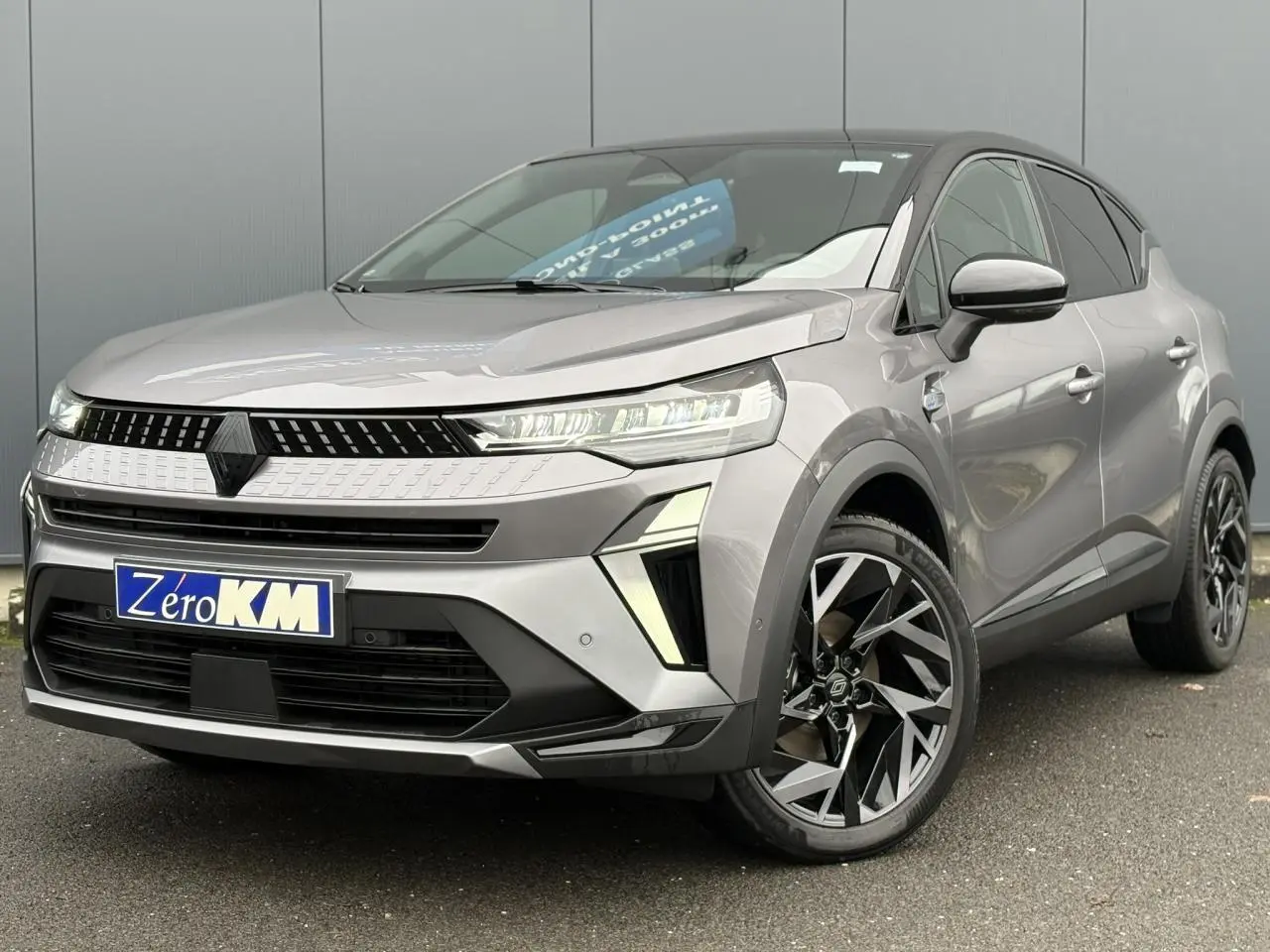 Vue 3/4 avant droit du Renault Captur 2025 gris Cassiopée avec jantes aluminium 19 pouces et toit noir étoilé.