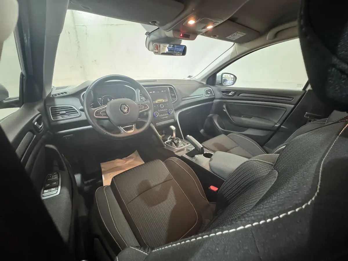 Vue intérieure avant droite de la Renault Mégane Business 2019, volant cuir multifonctions et écran tactile central visible.