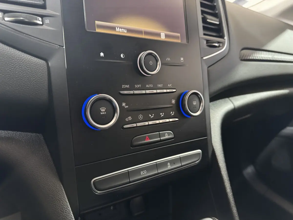 Vue rapprochée de la console centrale noire de la Renault Mégane Business avec commandes climatisation et écran tactile.