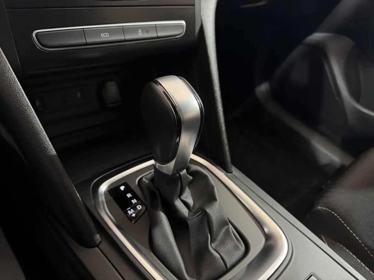 Gros plan sur la commande de boîte automatique noire et argentée dans l’habitacle sombre de la Renault Mégane Business 2019.
