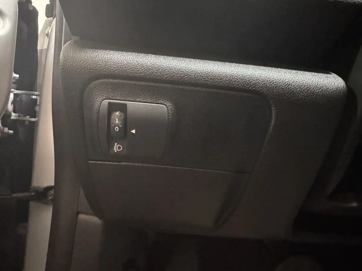 Gros plan sur le réglage de hauteur des phares côté gauche dans l’habitacle gris foncé de la Renault Mégane Business.