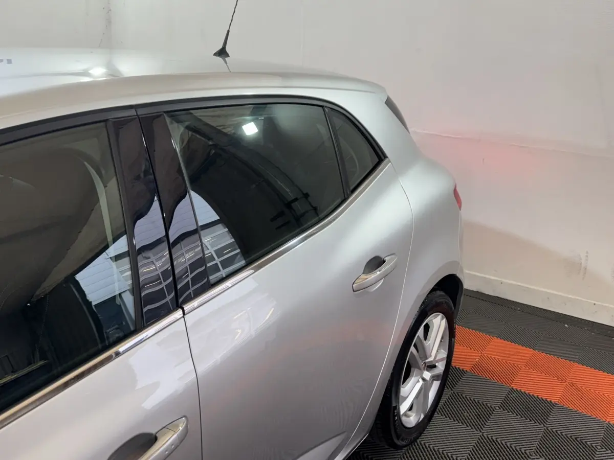 Vue côté droit arrière d'une Renault Mégane Business gris clair, avec jante alliage et vitres teintées.