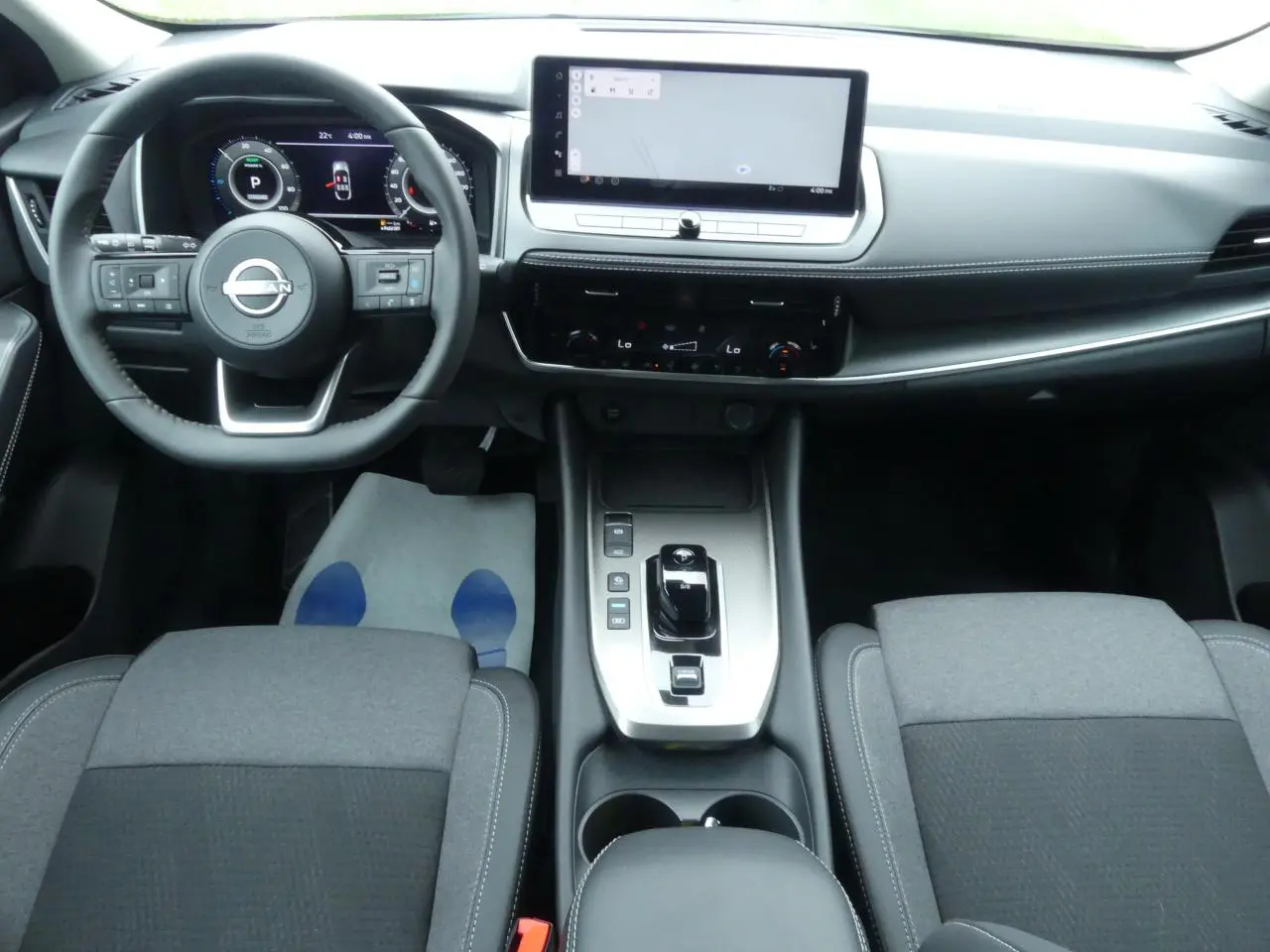 Vue intérieure avant du Nissan Qashqai 1.5 e-Power 2025, tableau de bord moderne avec écran tactile large et sellerie grise.