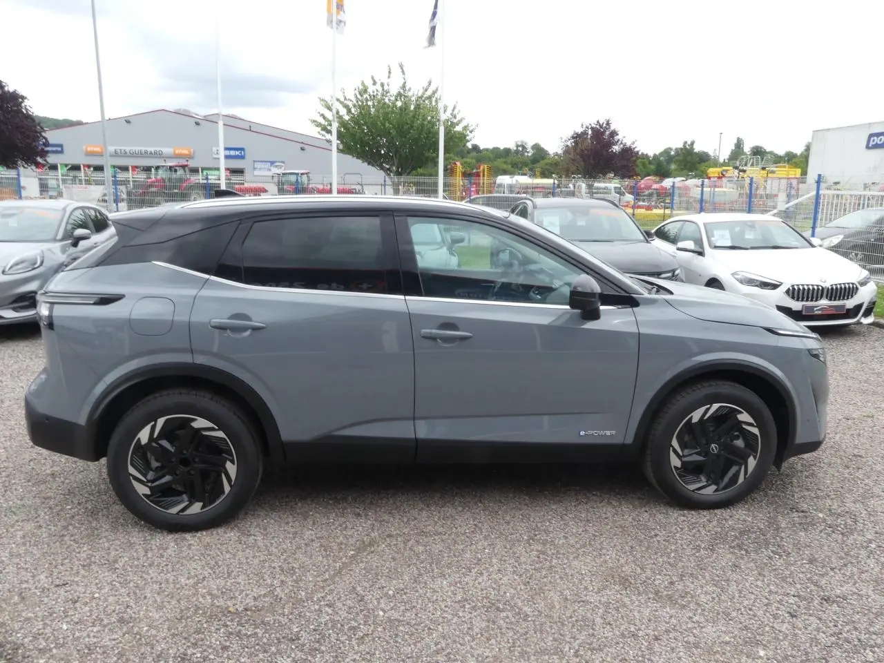 Vue de profil côté gauche du Nissan Qashqai 1.5 e-Power gris métallisé avec toit noir et jantes alliage noires.