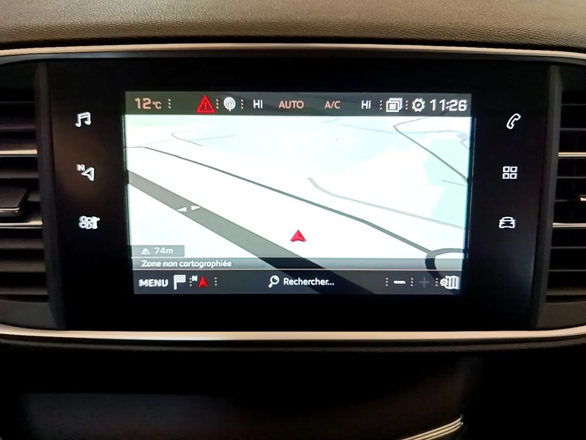 Écran tactile central du tableau de bord de la Peugeot 308 blanc, affichant la navigation GPS en mode carte.