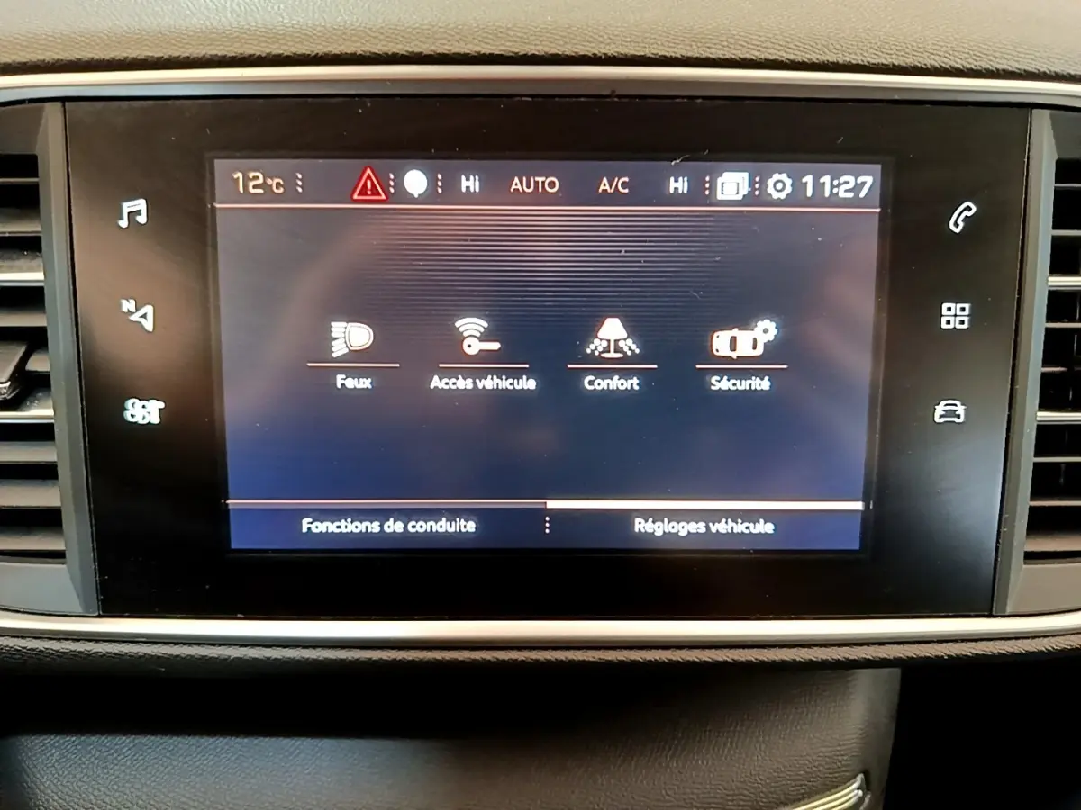 Écran tactile central de la Peugeot 308 blanc, affichant les réglages de conduite et sécurité.