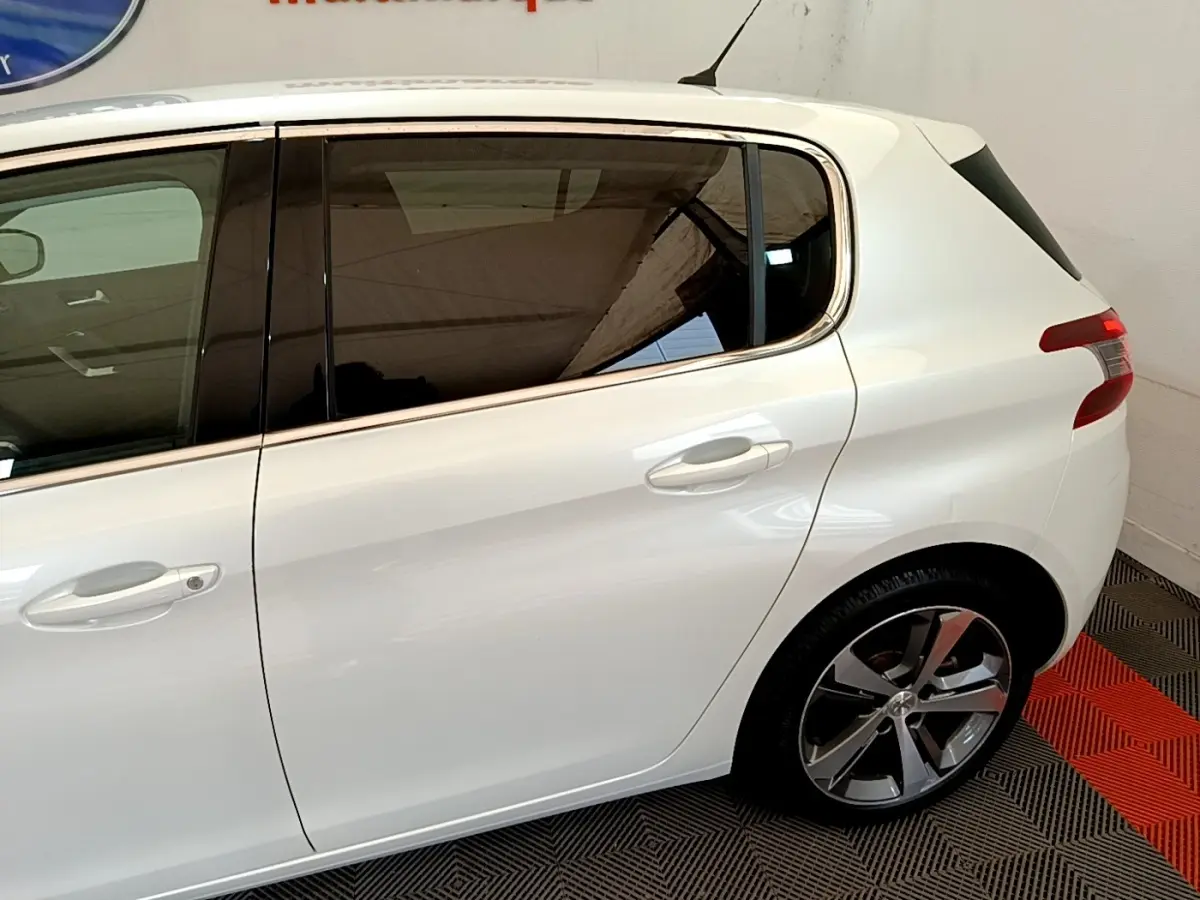 Vue latérale côté droit d'une Peugeot 308 blanche, mettant en valeur les vitres teintées et les jantes alliage.