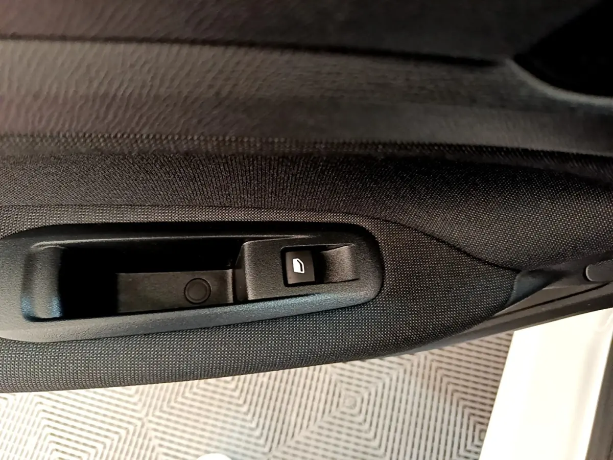 Bouton de commande de vitre sur la porte côté gauche d'une Peugeot 308 blanche vue de l'intérieur.