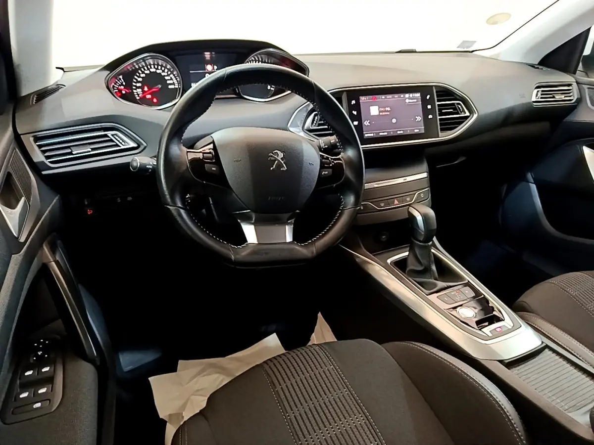 Vue intérieure avant de la Peugeot 308 2017, tableau de bord noir avec écran tactile et volant cuir multifonctions.