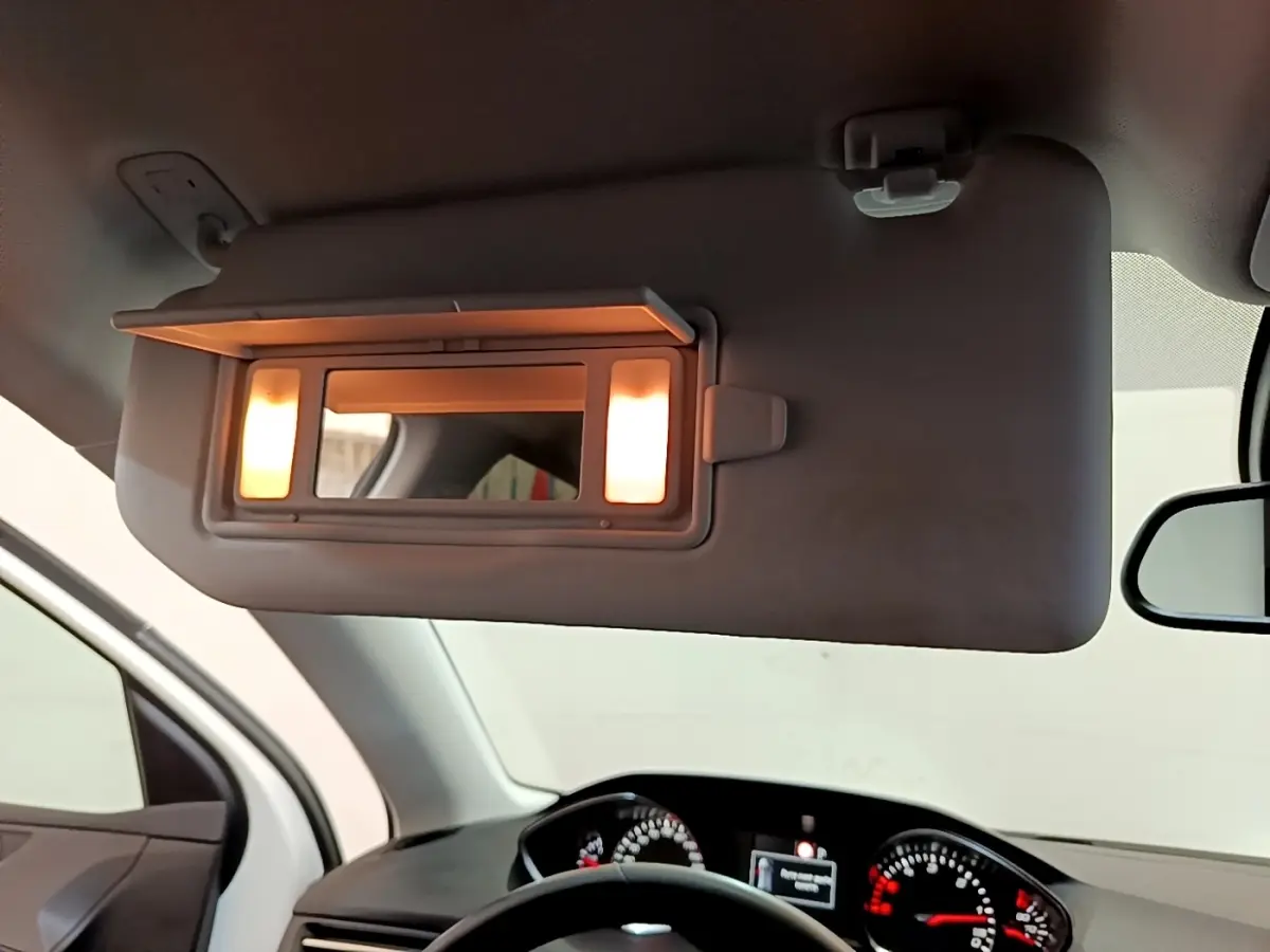 Détail intérieur du pare-soleil côté conducteur avec miroir éclairé, tableau de bord et volant Peugeot 308 visibles en arrière-plan.