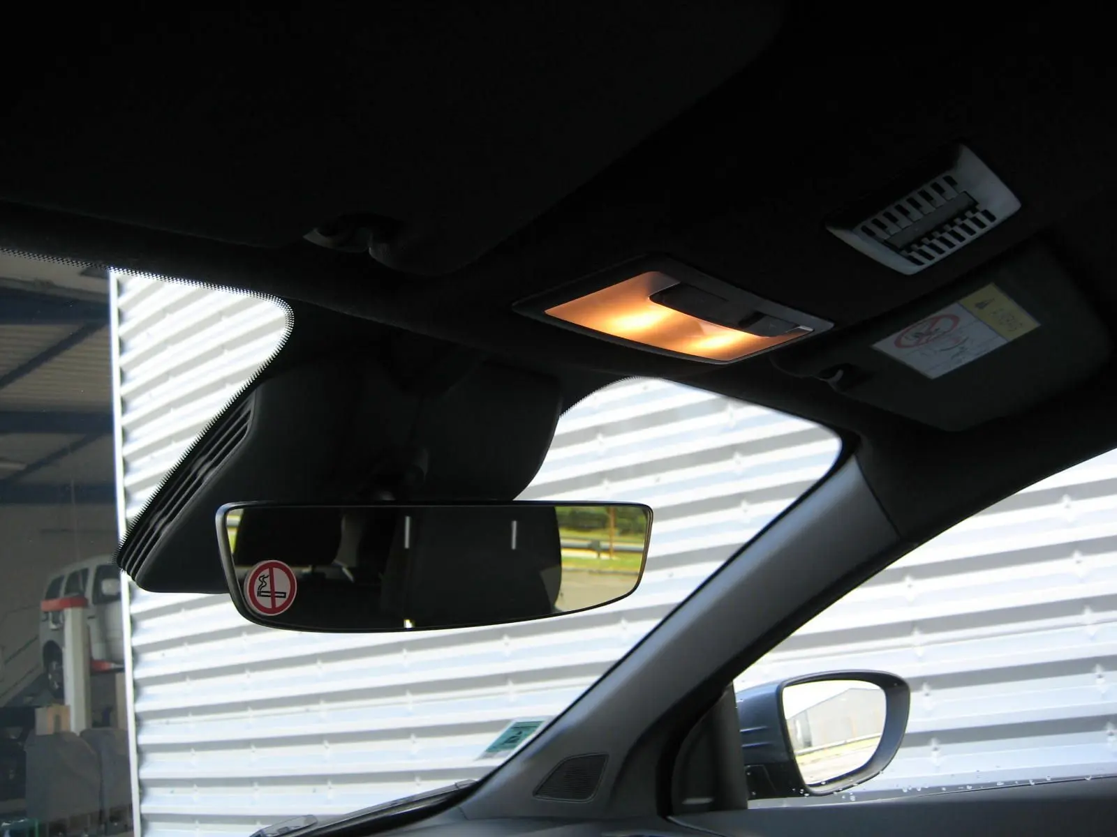 Vue intérieure côté conducteur du rétroviseur et du plafonnier allumé d'une MG3 1.5 Hybrid gris 2025.