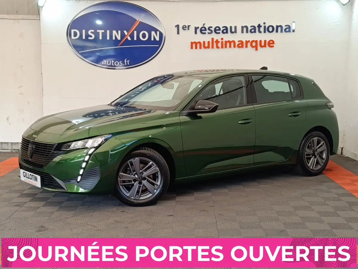 Peugeot 308 vert vue 3/4 avant droit, avec feux LED verticaux et jantes alliage, en intérieur showroom.