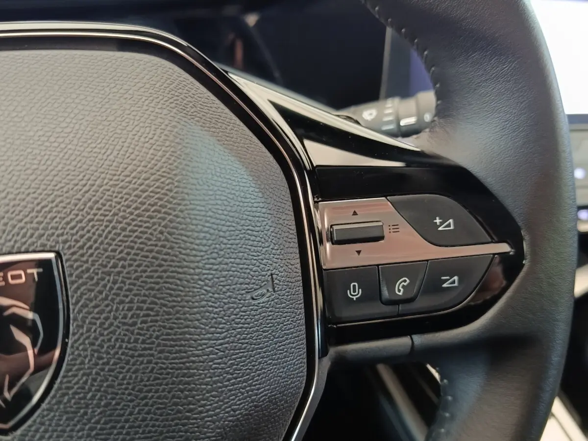Gros plan sur le volant cuir noir multifonctions de la Peugeot 308 2023 avec commandes vocales et audio intégrées.