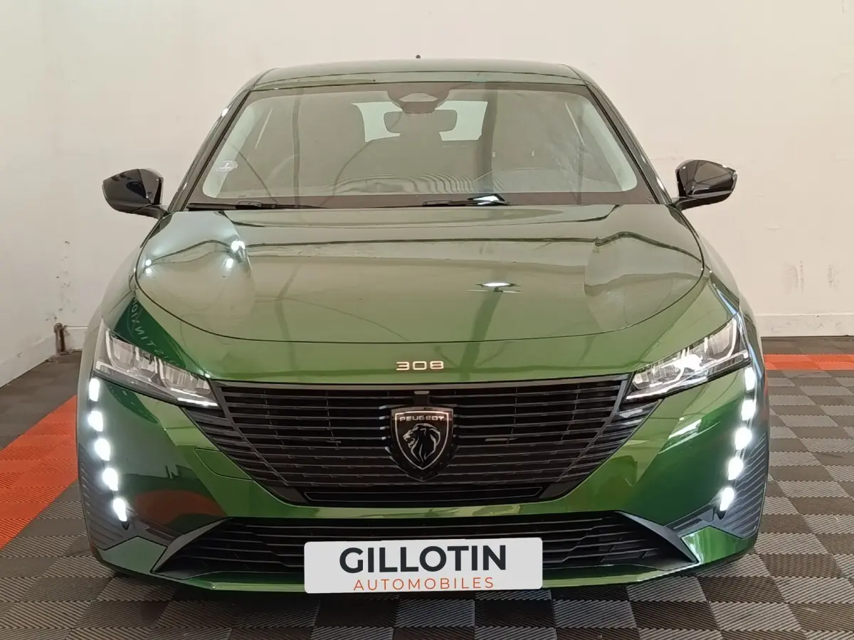 Vue avant d'une Peugeot 308 2023 vert métallisé avec feux diurnes LED verticaux et calandre noire distinctive.