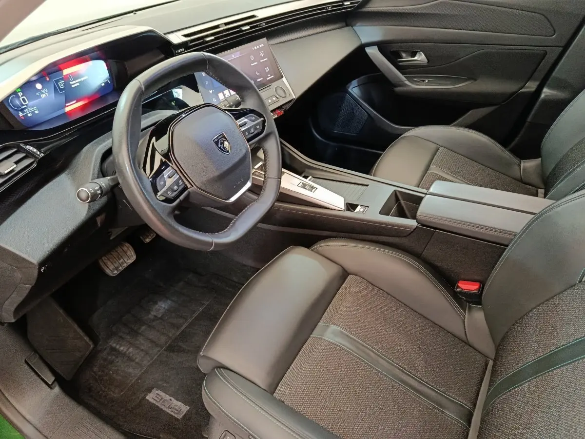 Vue intérieure côté conducteur de la Peugeot 308 2023, volant cuir multifonctions et tableau de bord digital.