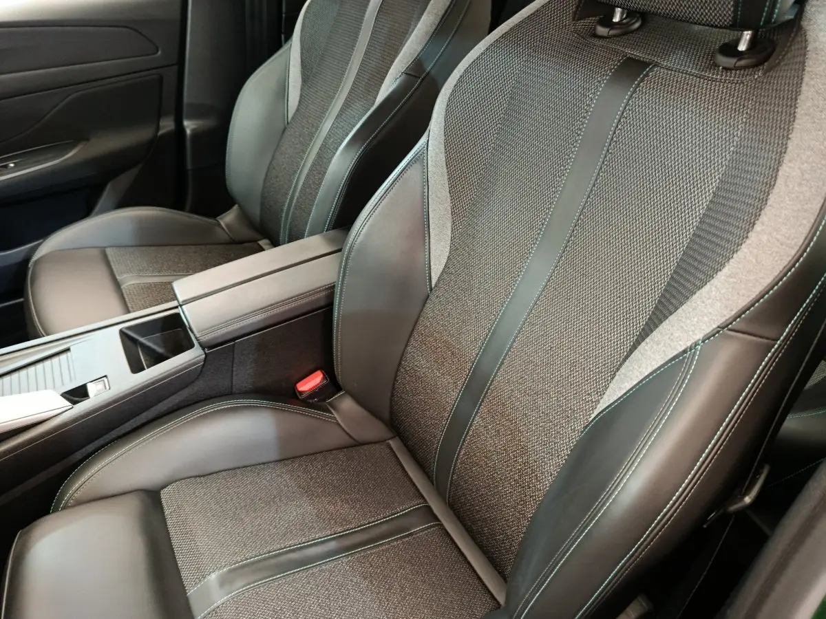Gros plan sur les sièges avant en cuir et tissu gris avec surpiqûres vertes de la Peugeot 308 2023.