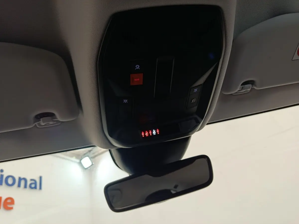 Vue intérieure du plafond avant de la Peugeot 308 2023, montrant le panneau de commandes avec bouton SOS rouge et rétroviseur central.