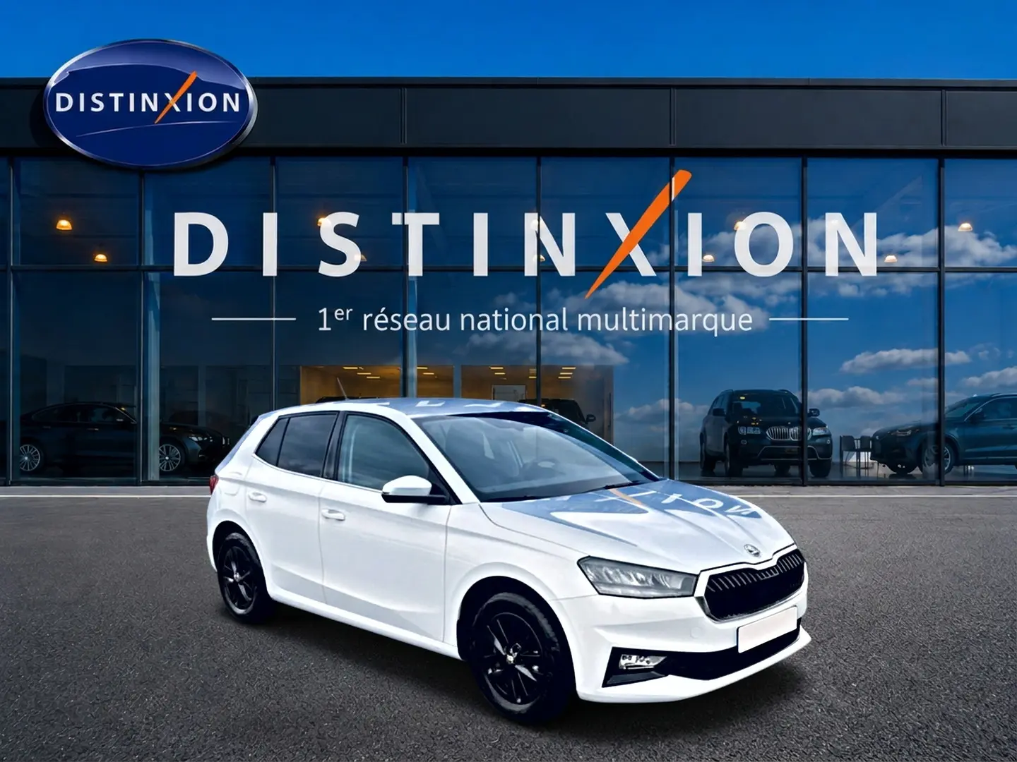 Vue 3/4 avant droite d'une Skoda Fabia blanche 2025 avec jantes noires devant un showroom Distinxion.