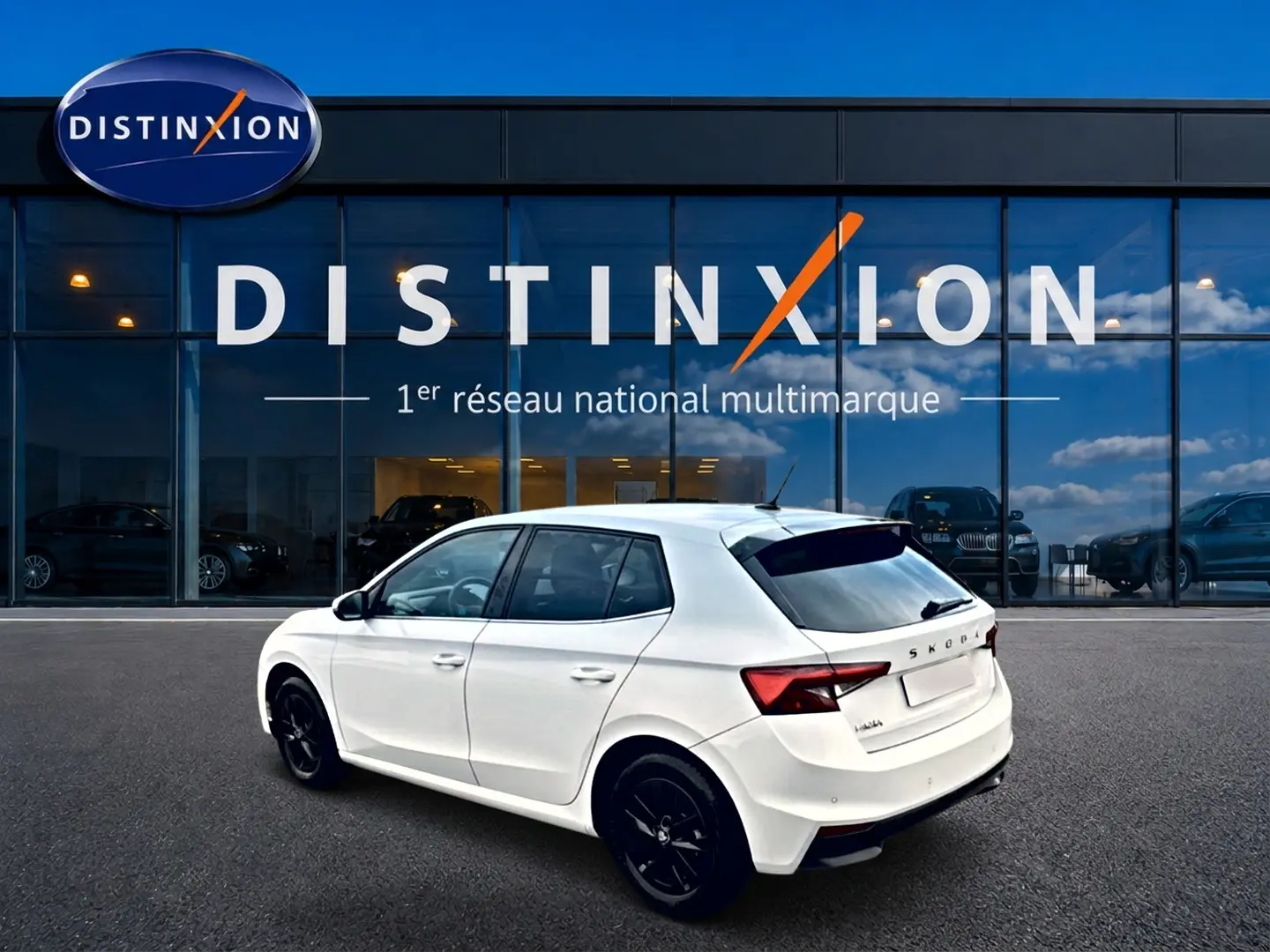 Vue 3/4 arrière droite d'une Skoda Fabia blanche 2025 avec jantes noires, stationnée devant une vitrine Distinxion.