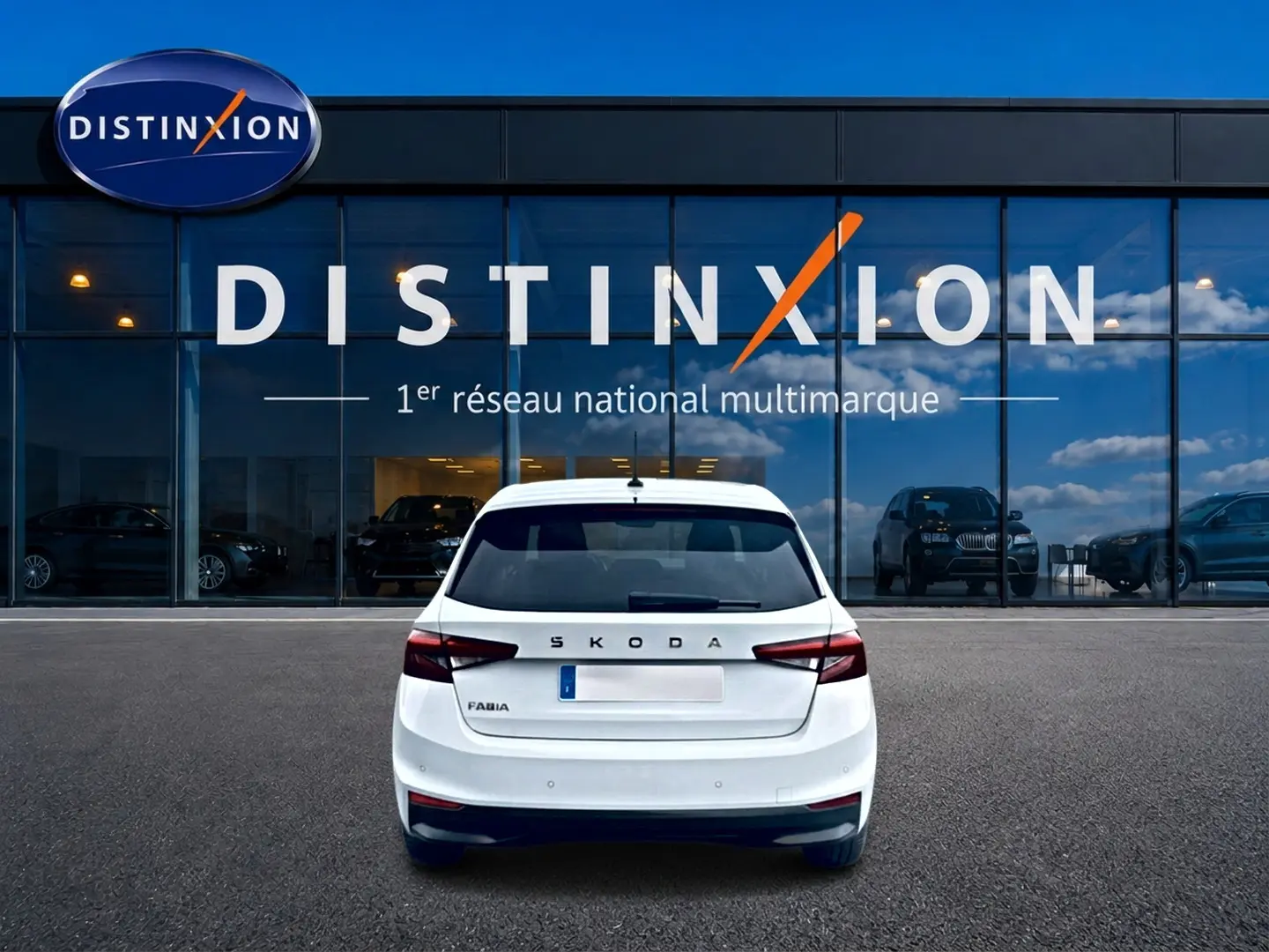 Vue arrière d'une Skoda Fabia blanche 2025 garée devant une vitrine avec logo Distinxion.