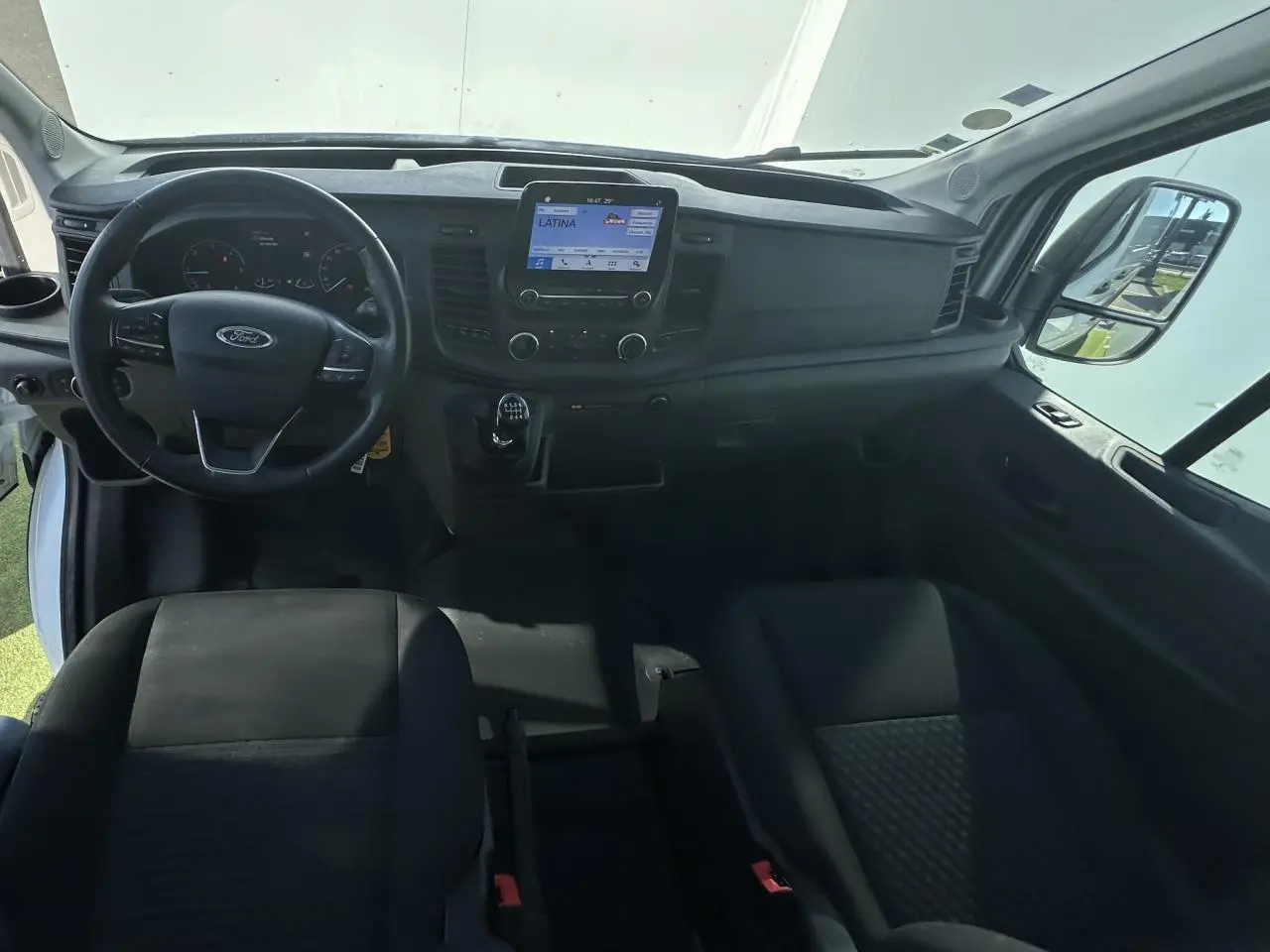 Vue intérieure avant du Ford Transit Fourgon blanc 2020, tableau de bord avec écran tactile et volant multifonction.