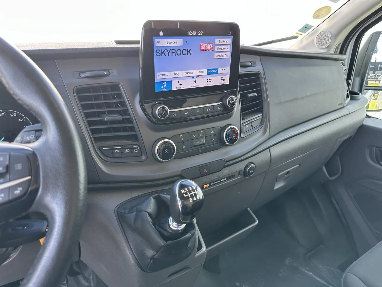 Intérieur du Ford Transit Fourgon 2020, vue du tableau de bord avec écran tactile et levier de vitesses manuel en premier plan.