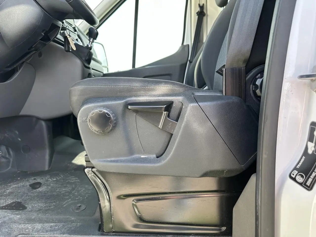 Gros plan sur le siège conducteur noir du Ford Transit Fourgon blanc, avec réglages manuels visibles côté gauche.