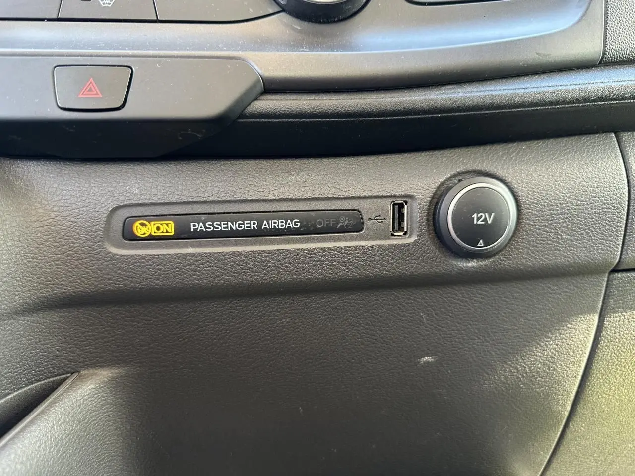 Gros plan sur le tableau de bord noir du Ford Transit Fourgon 2020 montrant témoin airbag passager activé et prise 12V.