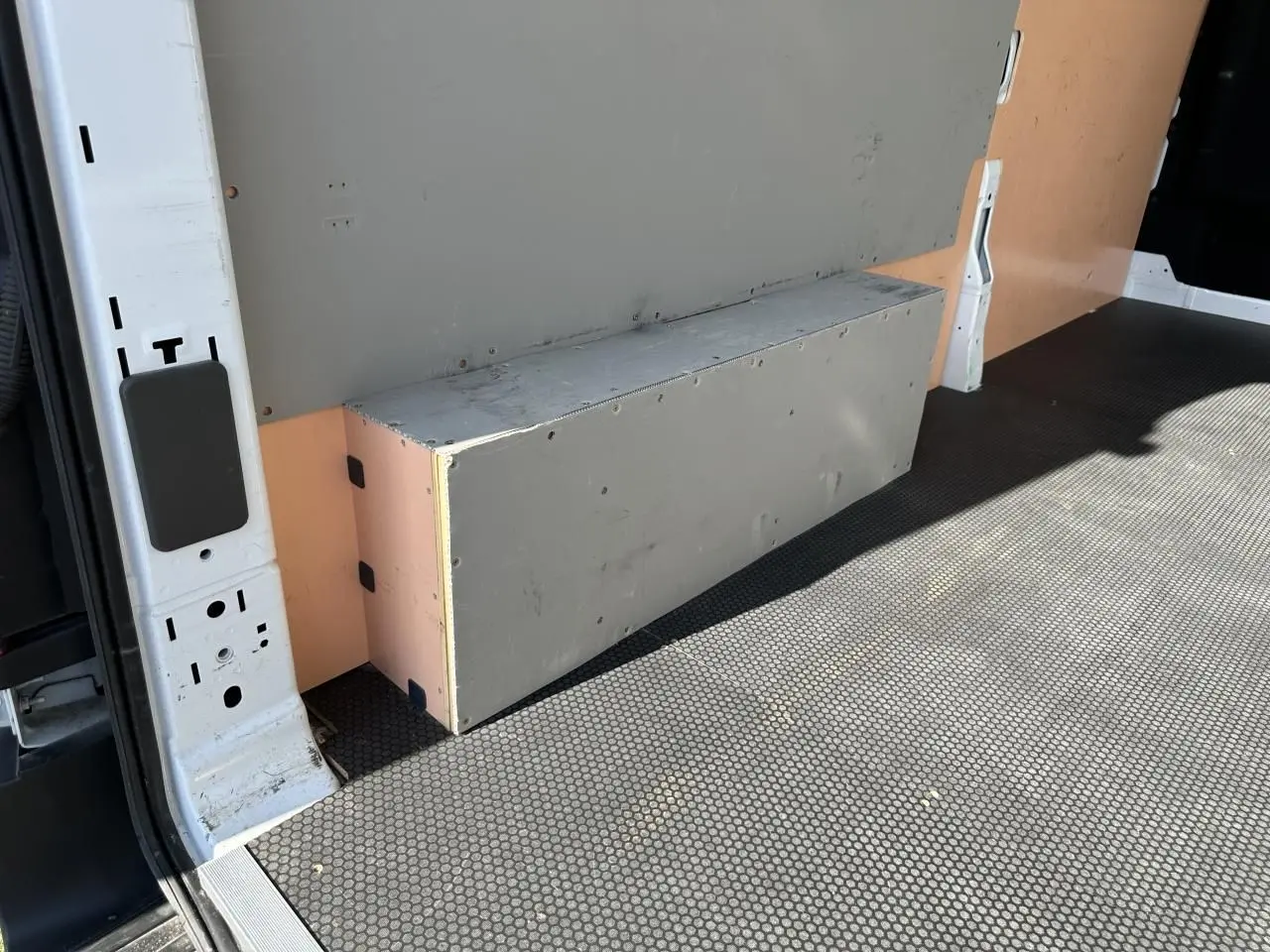 Détail de l'intérieur du fourgon Ford Transit blanc, montrant le revêtement et un caisson gris côté gauche.