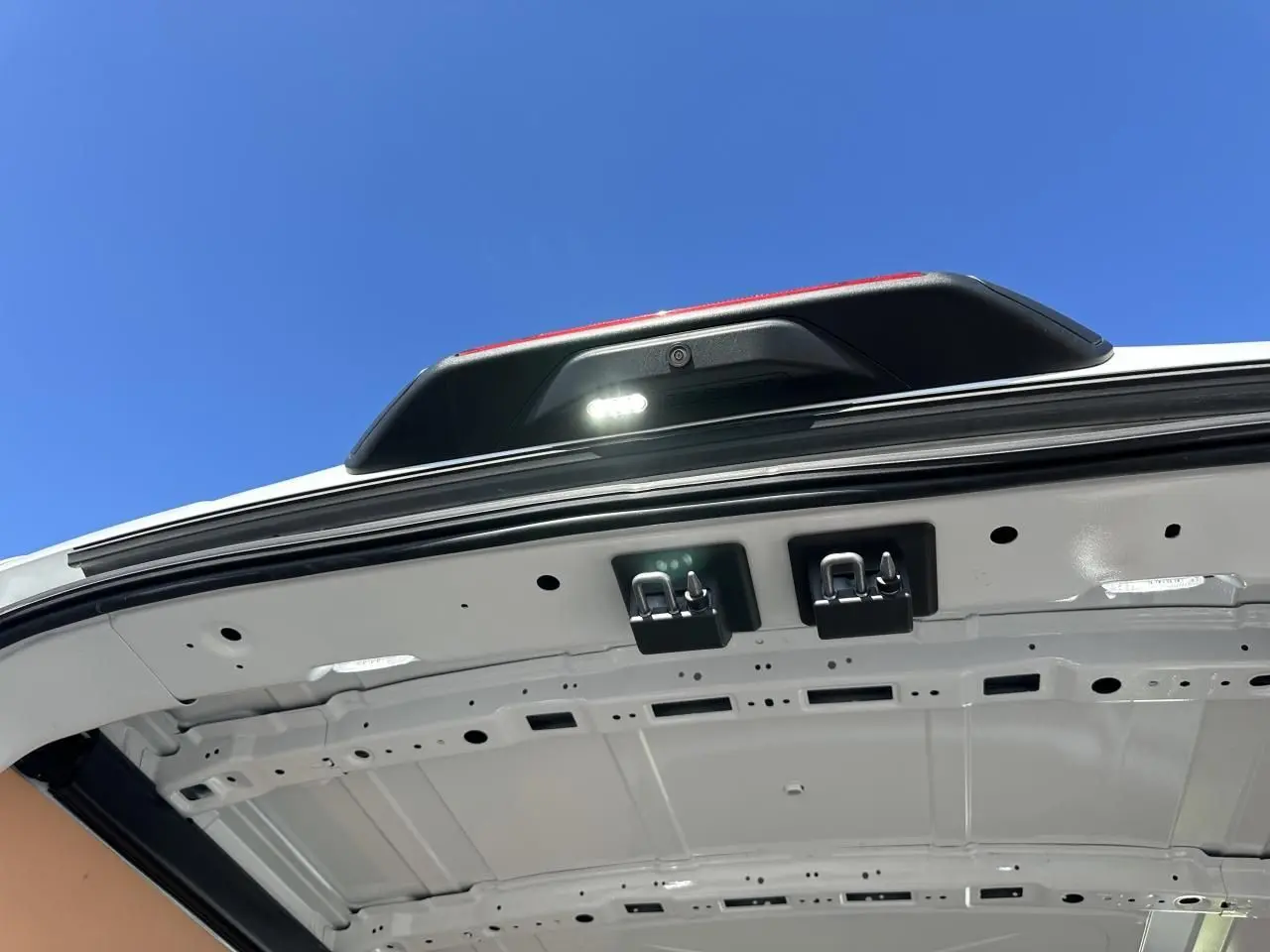 Vue en contre-plongée de l'intérieur de la porte arrière blanche du Ford Transit Fourgon avec caméra de recul et éclairage LED.
