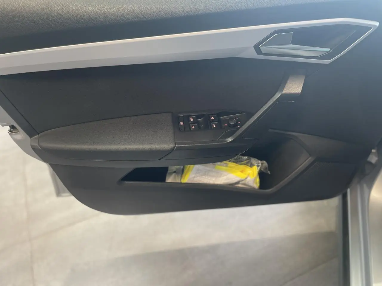 Gros plan sur la porte avant gauche noire du SEAT Arona 2024, avec commandes électriques des vitres et poignée argentée.