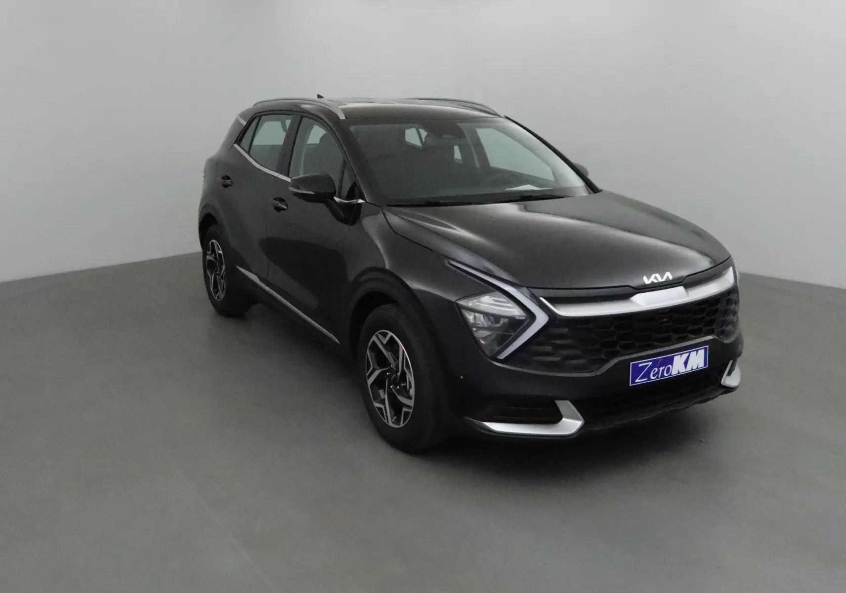 KIA Sportage noir 2025 en 3/4 avant droit, avec calandre distinctive et jantes alliage modernes.