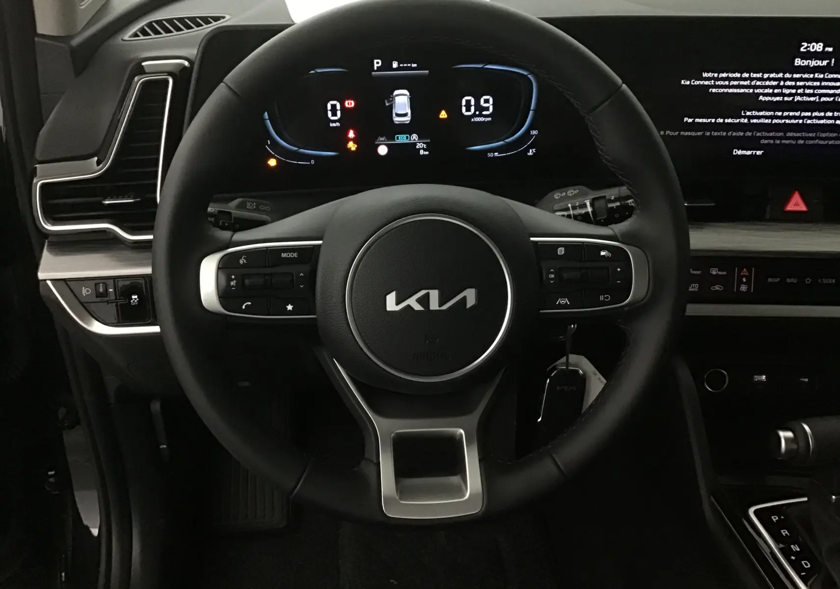 Vue rapprochée du volant cuir noir du Kia Sportage 2025 avec tableau de bord digital et écran tactile à droite.
