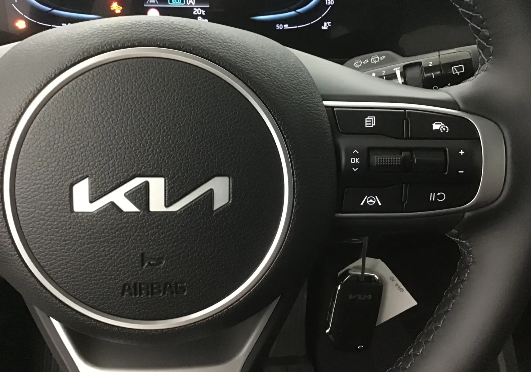 Gros plan sur le volant noir en cuir du Kia Sportage 2025 avec commandes intégrées et logo moderne au centre.