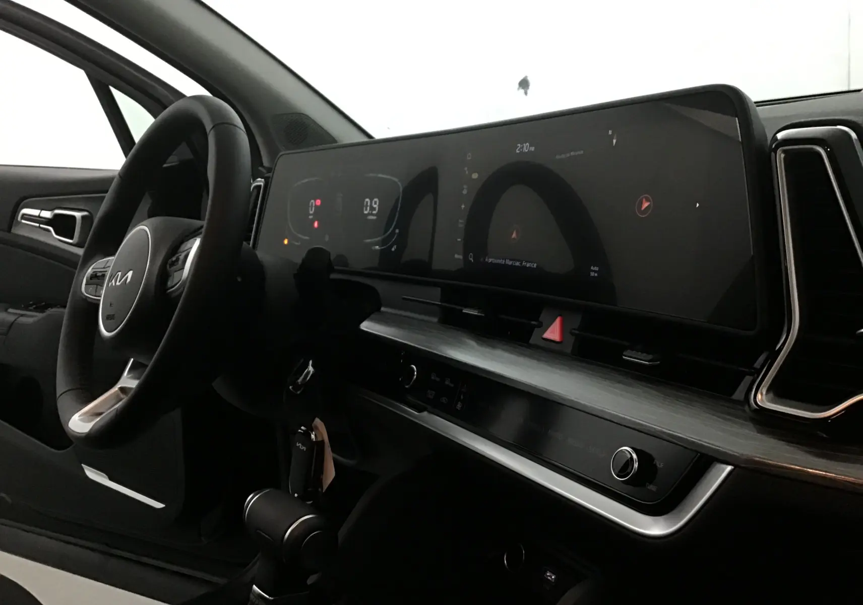 Intérieur du Kia Sportage 2025 vu côté conducteur, tableau de bord moderne avec écran digital large de 12,3 pouces.