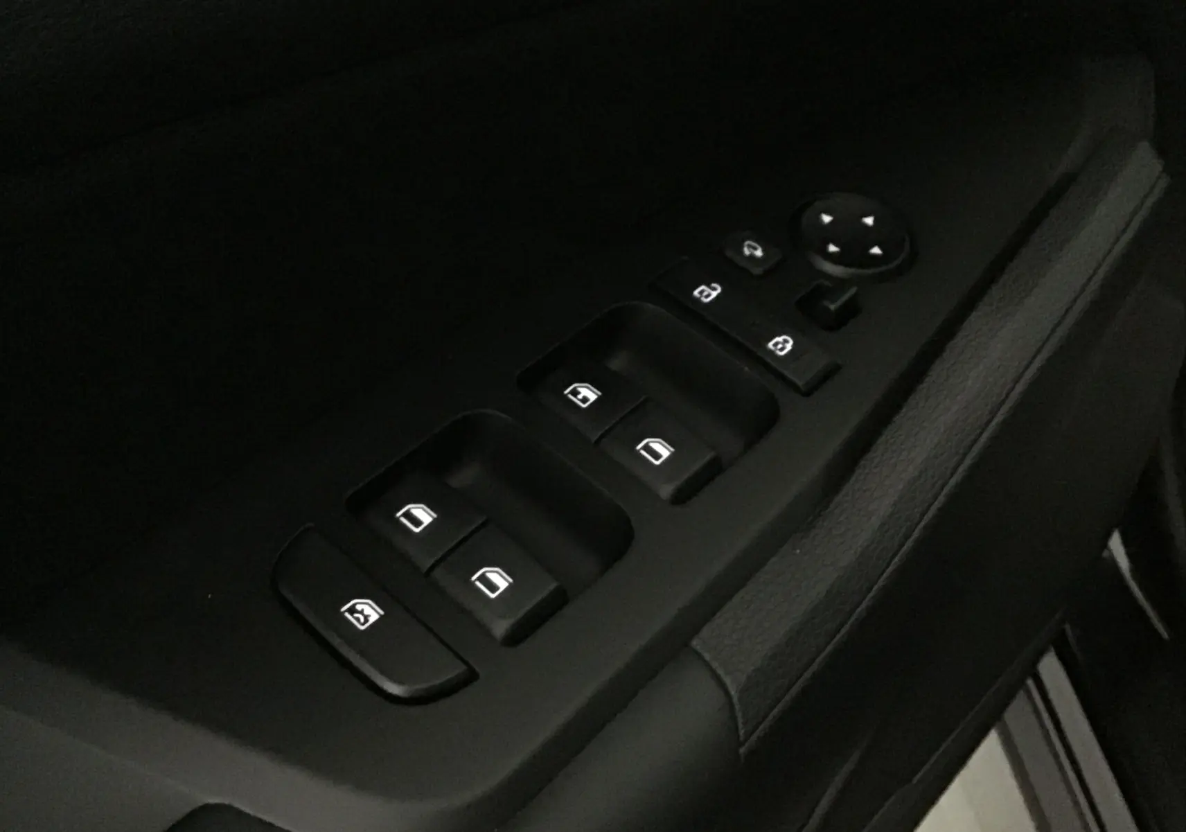 Gros plan sur les commandes des vitres électriques et rétroviseurs côté conducteur du Kia Sportage noir 2025.