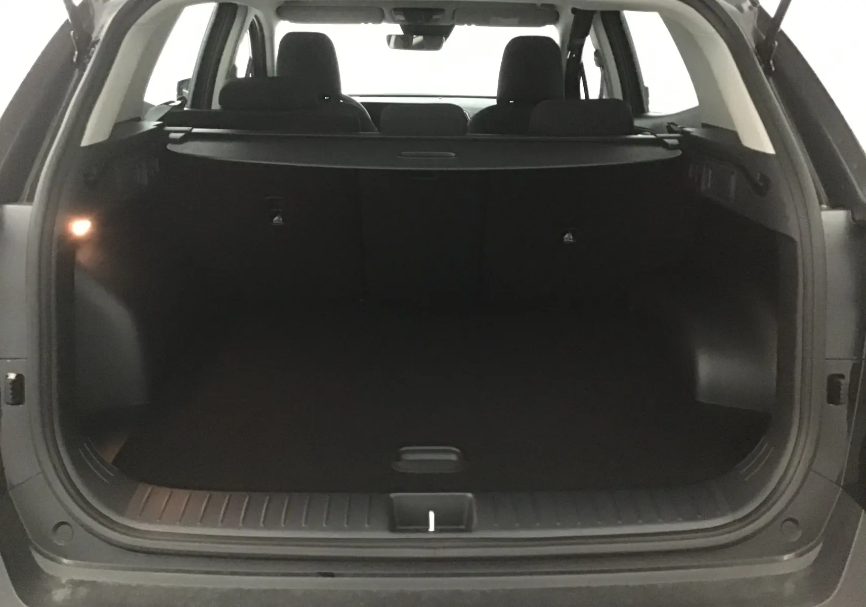 Coffre ouvert du Kia Sportage noir 2025, vue arrière montrant l'espace de chargement et la plage arrière.