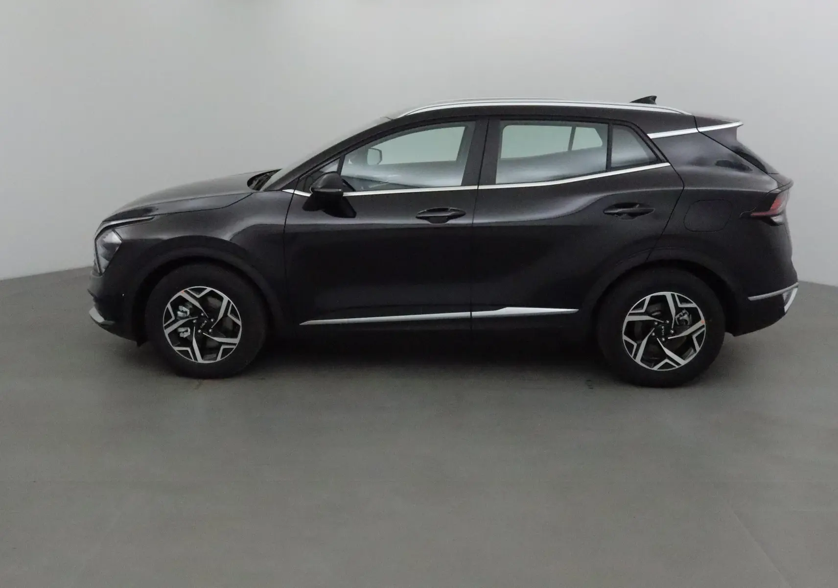 Vue latérale côté gauche d'un KIA SPORTAGE noir 2025 avec jantes alliage et lignes de carrosserie sculptées.