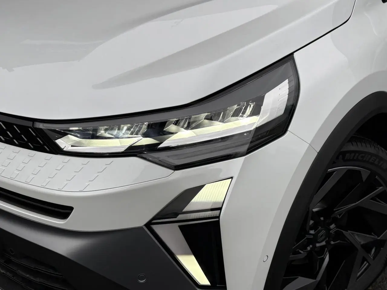 Gros plan sur l'avant droit du Renault Captur blanc nacré, mettant en valeur le phare LED et la jante aluminium noire.