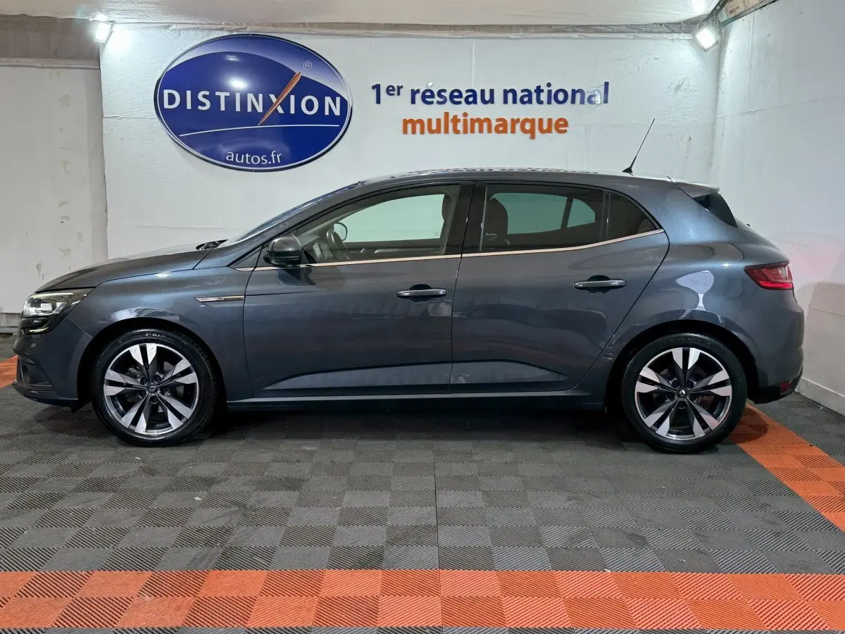 Profil côté gauche d'une Renault Mégane Intens gris foncé 2019, avec jantes alliage et vitres teintées en intérieur showroom.