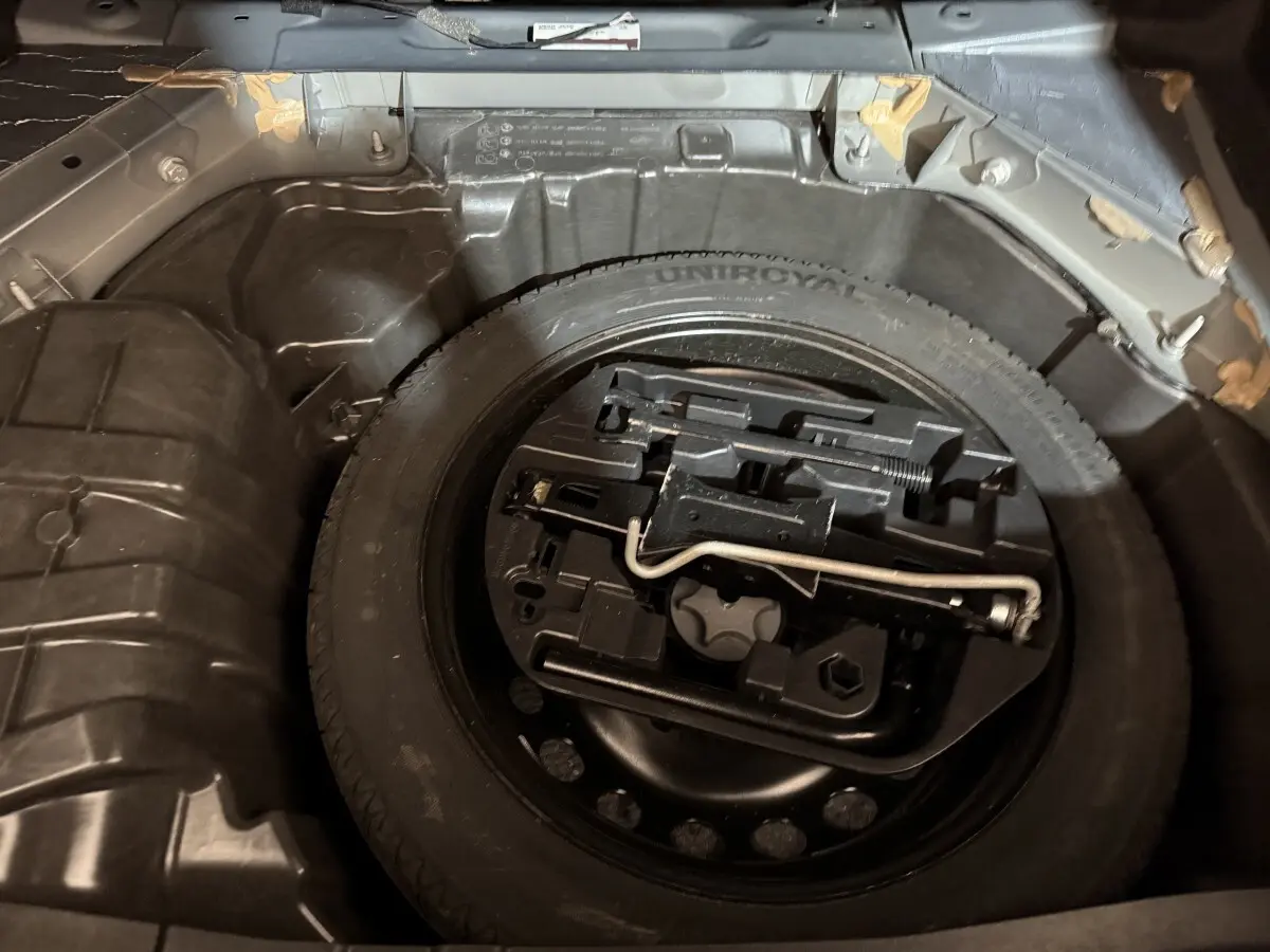 Vue rapprochée de la roue de secours et des outils dans le coffre d’une Renault Mégane gris foncé 2019.