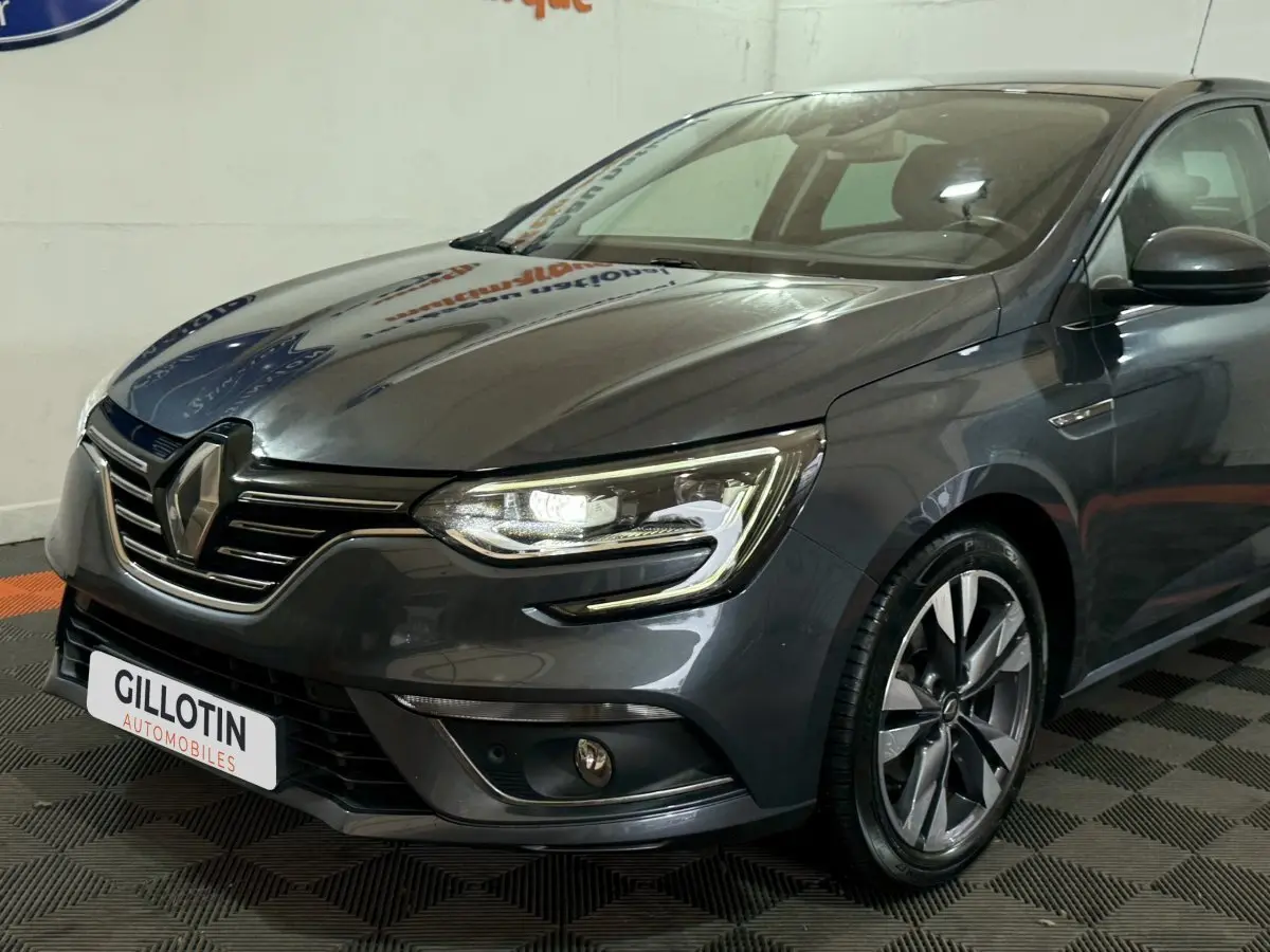 Renault Mégane Intens gris foncé vue 3/4 avant droit, phares LED et jantes alliage distinctives visibles.